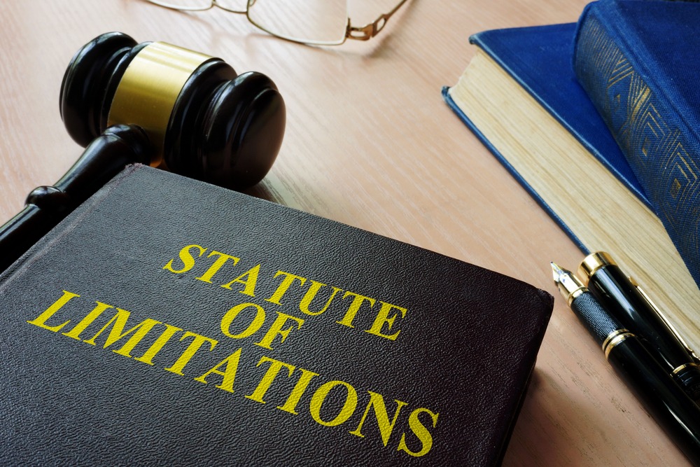 Large legal books with the text "Statute of Limitations" on the front sitting on a court desk